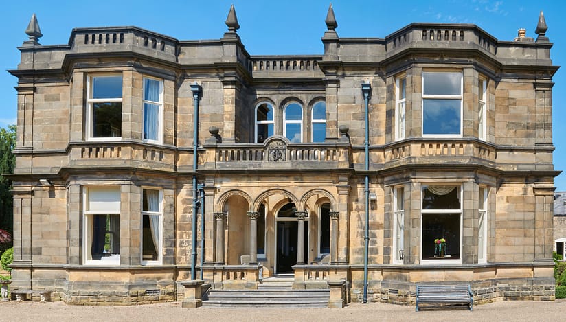 Stretton House, Derbyshire – Ashlar stone country house with castellated roofline, arched windows and central entrance portico.