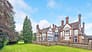 Kingswood Manor, Surrey – Tudor-style country house with brick and half-timber façade, tall chimneys, and manicured lawns.