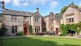 Morland House, Cumbria – Stone and red-brick country house with slate roof, manicured lawn, and patio seating area.