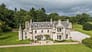 Wardhill Castle, Aberdeenshire – Stone castle with crenellated towers and turrets, surrounded by manicured lawns and mature woodland.